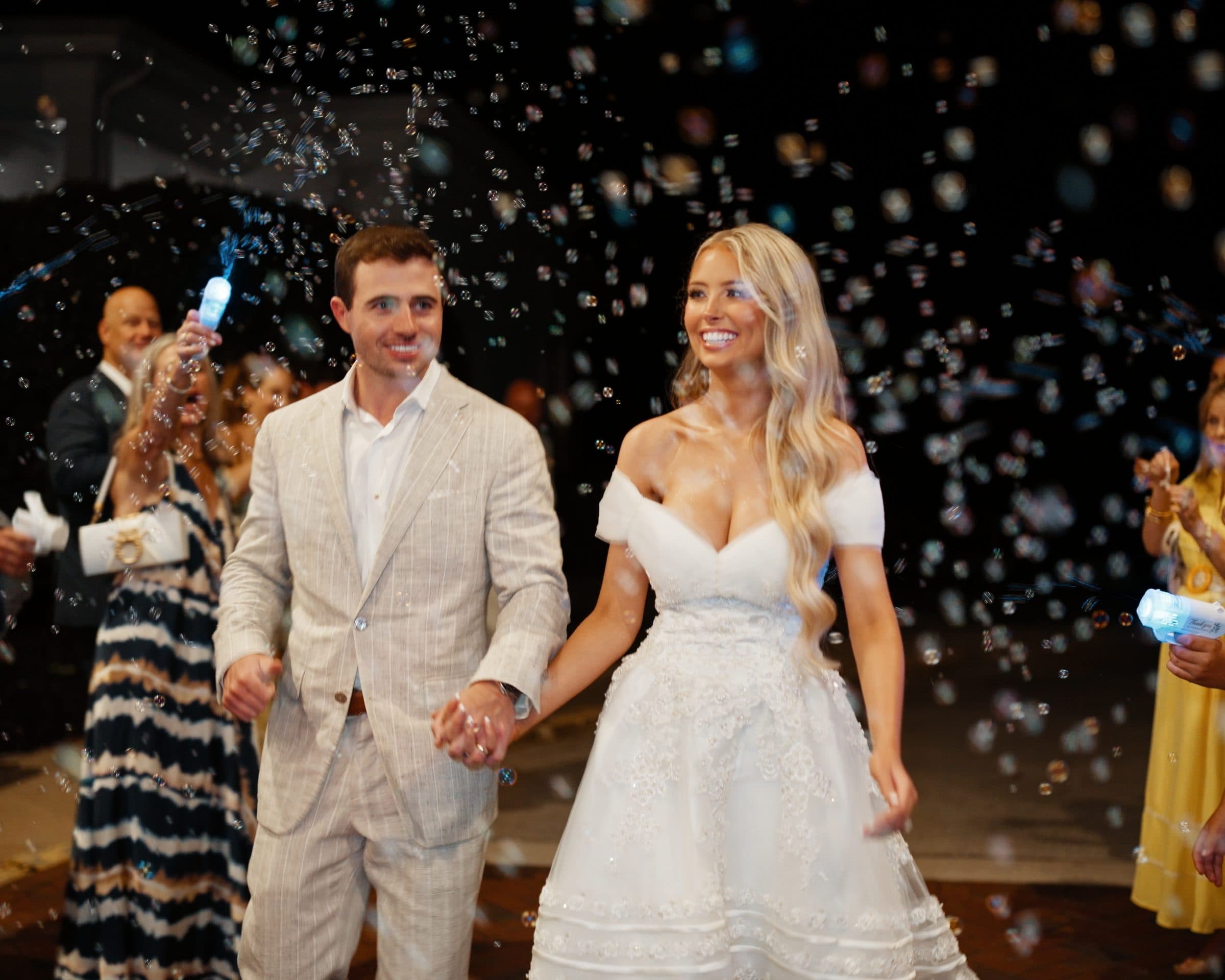 A couple's send-off through a cloud of bubbles at night
