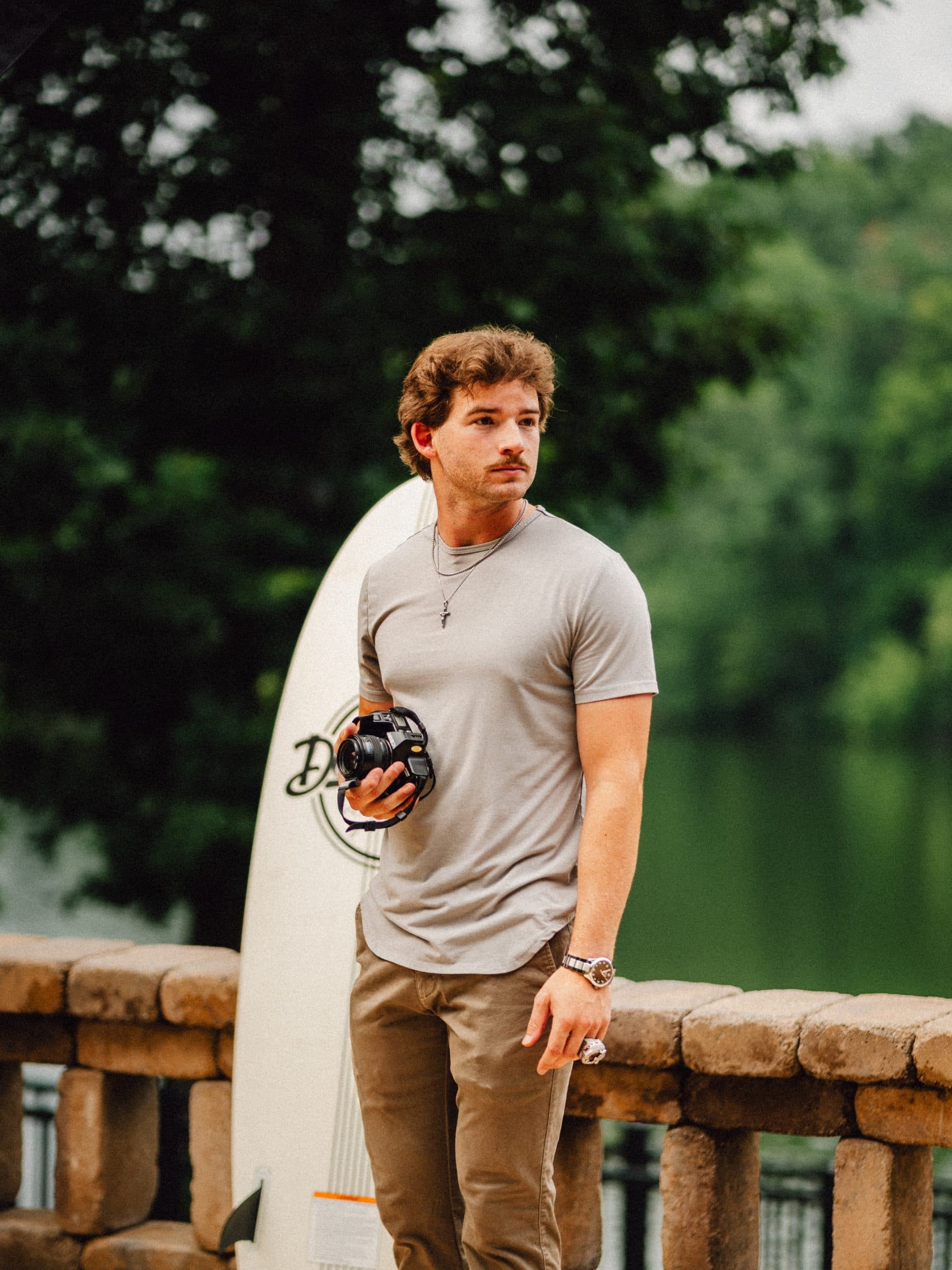 Rowe holding a surfboard by the river